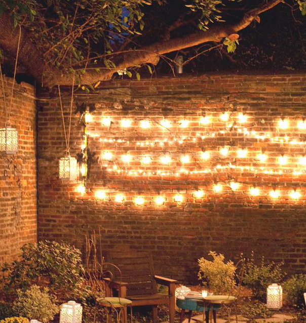 Backyard patio string lighting on brick wall